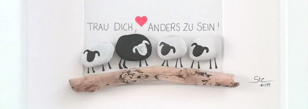 Stein-Bild mit 3 weißen Schafen und einem schwarzen Schaf, mit dem Spruch 'Trau dich, anders zu sein!'